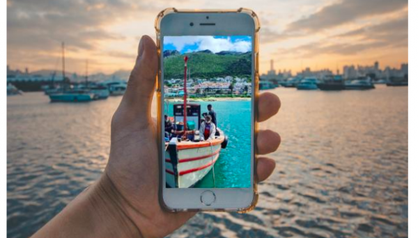 Screenshot of title and holding a phone with an image showing a fishing boat